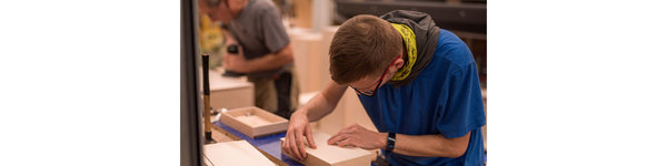 Ein Mitarbeiter fertigt eine Box aus Holz für Fotos an
